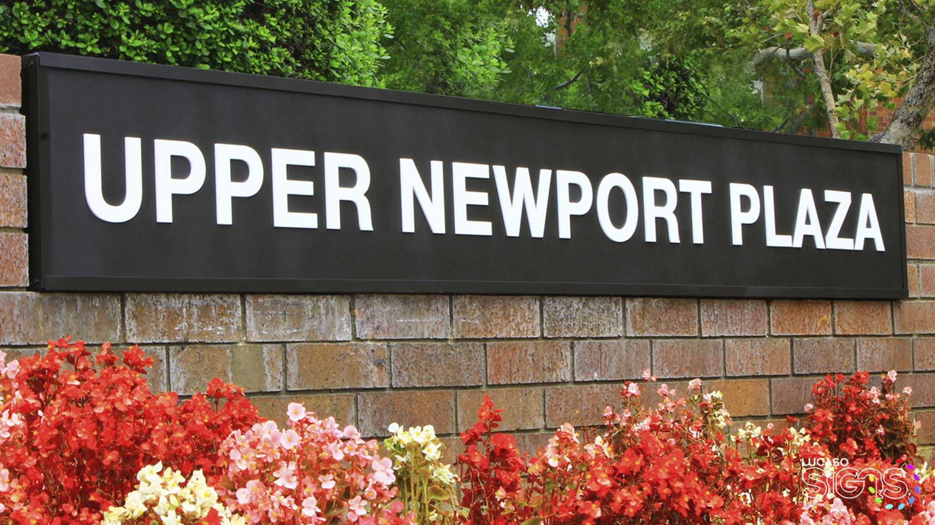 Custom monument light box sign with white lettering for Upper Newport Plaza mounted on brick wall by Lucaso Signs
