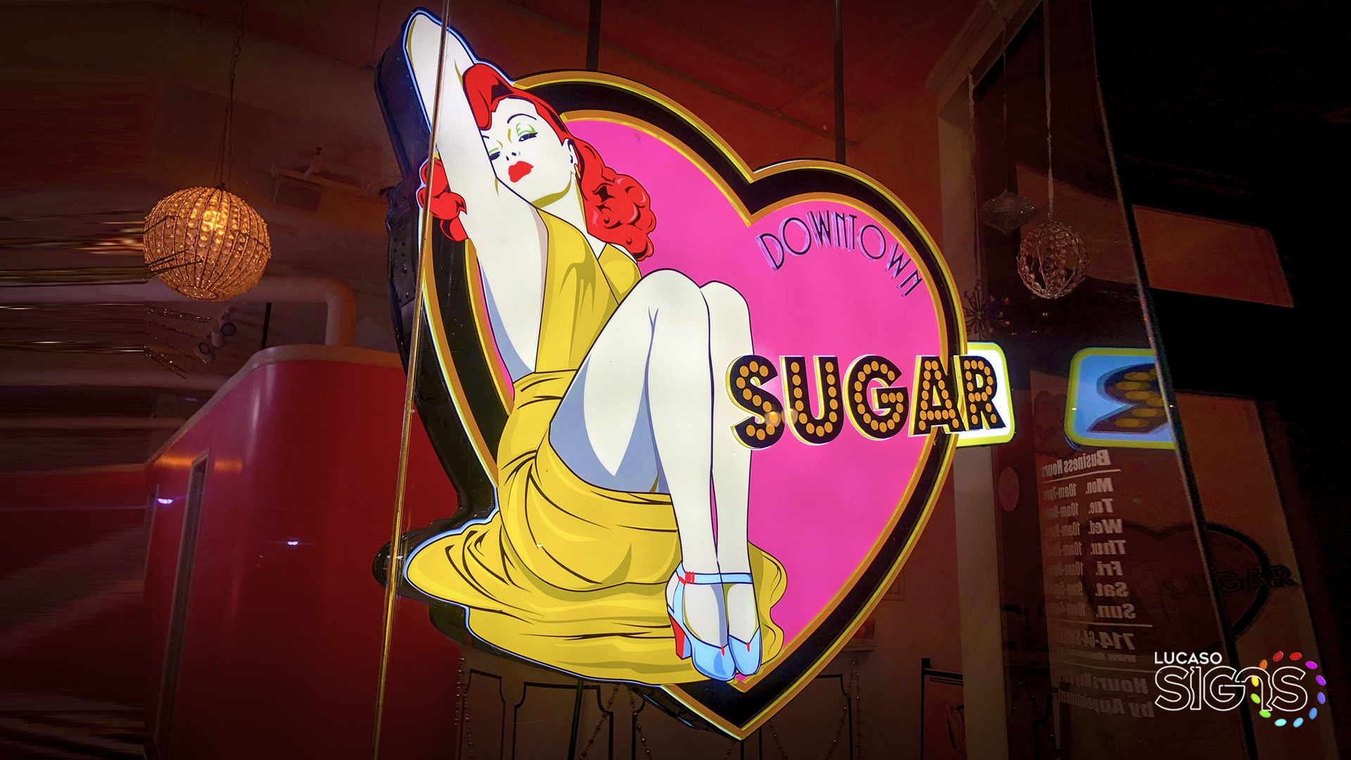 Colorful illuminated heart-shaped window sign with retro pin-up girl illustration and glowing SUGAR text, custom design by Lucaso Signs