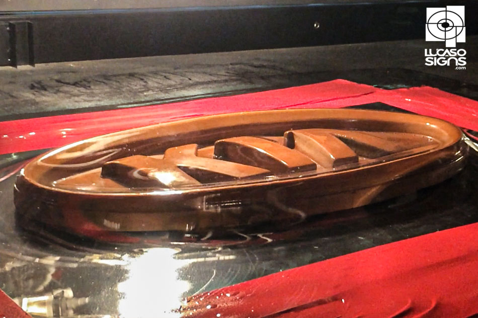 Thermoforming process of creating a 3D KIA car logo emblem using heated plastic sheet molded over form, custom fabrication by Lucaso Signs